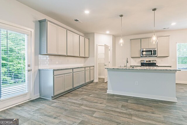 kitchen featuring stainless steel appliances, hanging light fixtures, plenty of natural light, and gray cabinetry