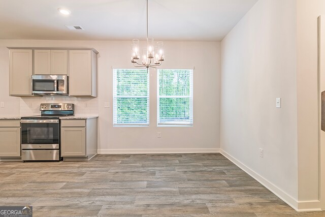 kitchen featuring a chandelier, tasteful backsplash, light hardwood / wood-style flooring, gray cabinetry, and appliances with stainless steel finishes