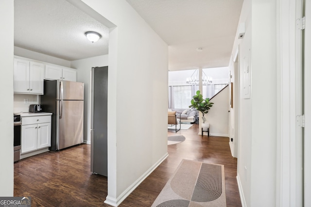 corridor featuring an inviting chandelier, a textured ceiling, and dark wood-type flooring