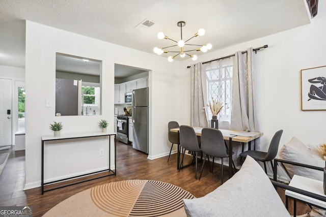 dining area with a textured ceiling, a notable chandelier, plenty of natural light, and dark hardwood / wood-style flooring