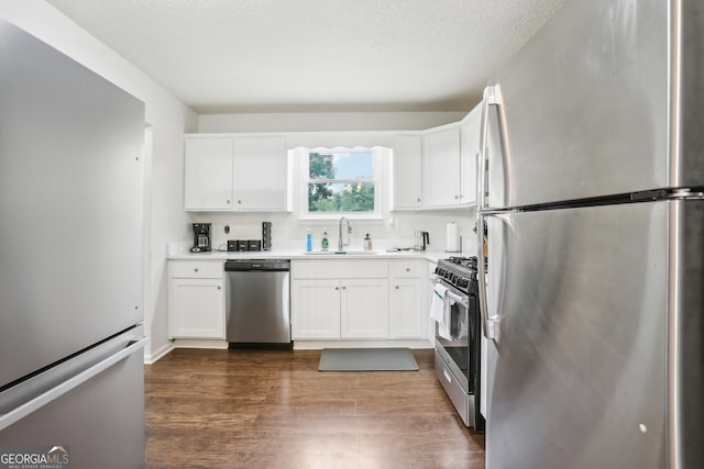 kitchen with white cabinetry, sink, dark hardwood / wood-style floors, appliances with stainless steel finishes, and a textured ceiling