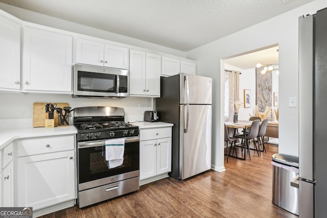 kitchen featuring hardwood / wood-style flooring, white cabinetry, stainless steel appliances, and a textured ceiling