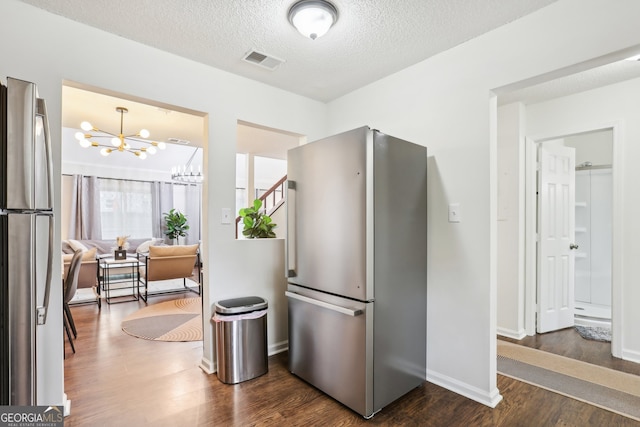 kitchen with dark wood-type flooring, stainless steel refrigerator, and a textured ceiling