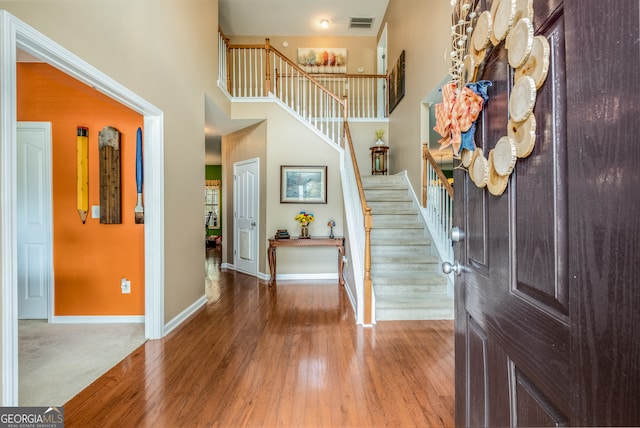 foyer entrance featuring wood-type flooring and a high ceiling