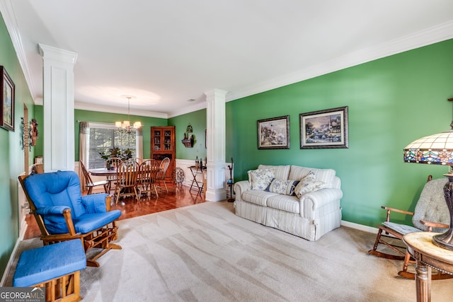 living room featuring a notable chandelier, light hardwood / wood-style floors, crown molding, and ornate columns