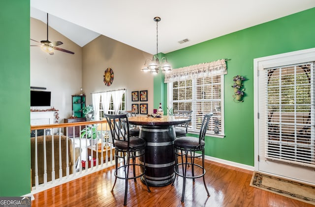 dining space featuring ceiling fan with notable chandelier, vaulted ceiling, and hardwood / wood-style flooring