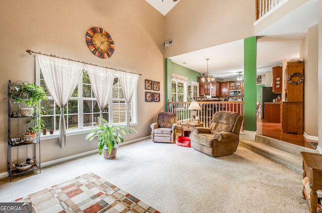 carpeted living room featuring ceiling fan and a high ceiling