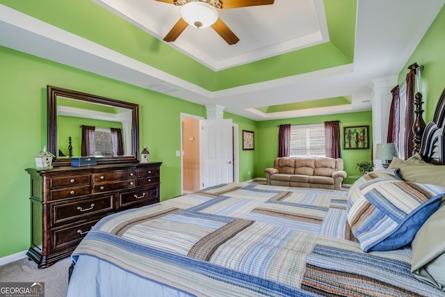 carpeted bedroom with ceiling fan and a raised ceiling