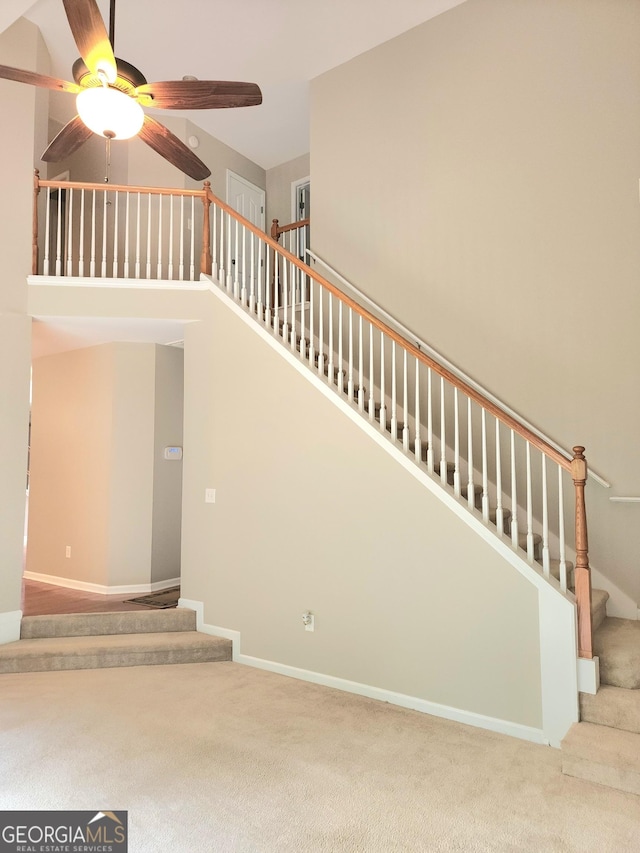 stairway with carpet floors and ceiling fan