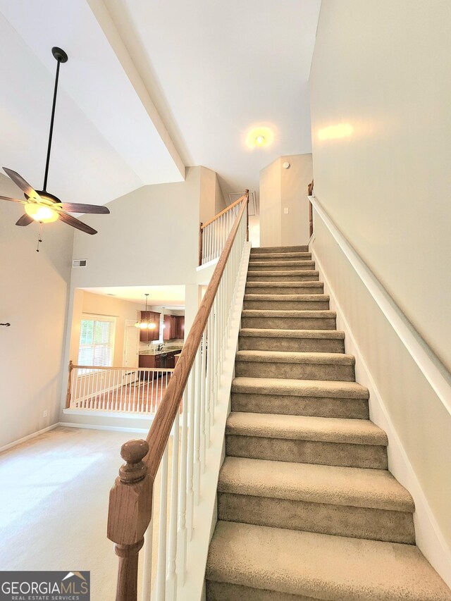 stairway featuring high vaulted ceiling, ceiling fan, carpet, and visible vents