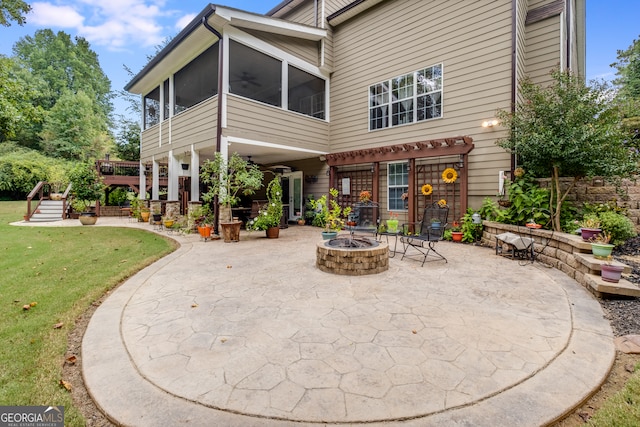 rear view of property featuring a patio, a yard, a sunroom, and an outdoor fire pit