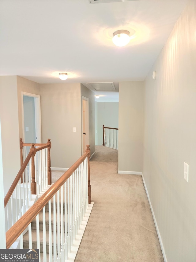hall featuring light carpet, attic access, and an upstairs landing