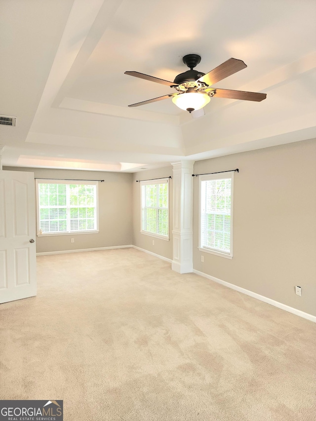 spare room featuring a tray ceiling, light colored carpet, and visible vents