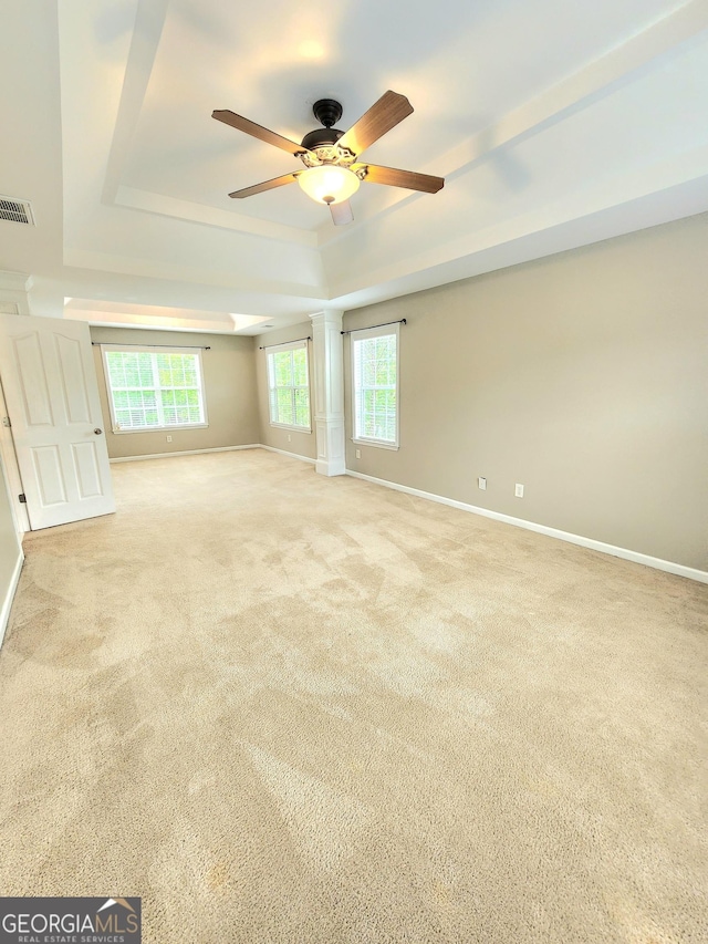 carpeted empty room with visible vents, baseboards, ceiling fan, and a tray ceiling