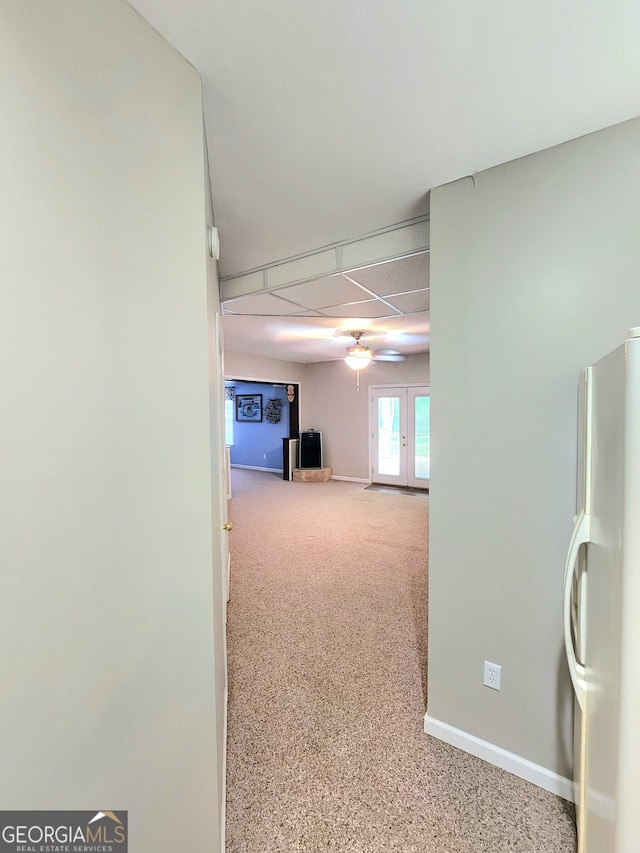 hallway featuring carpet floors, baseboards, and french doors