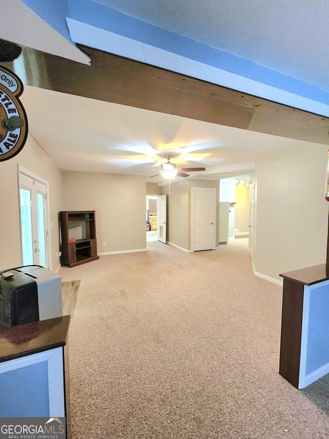 unfurnished living room featuring baseboards, a ceiling fan, and light colored carpet