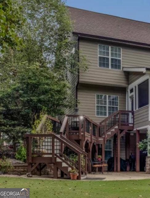 back of property featuring a lawn, stairs, and a deck