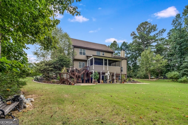 back of house with a chimney, a lawn, a sunroom, a patio, and stairs