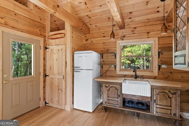 kitchen with lofted ceiling with beams, plenty of natural light, hanging light fixtures, and white fridge