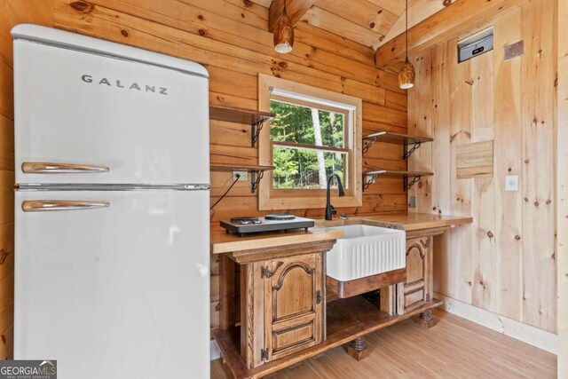 interior space featuring light hardwood / wood-style floors, beamed ceiling, wooden ceiling, wooden walls, and sink