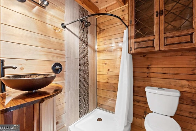 bathroom with wood walls, toilet, vanity, and a shower with curtain