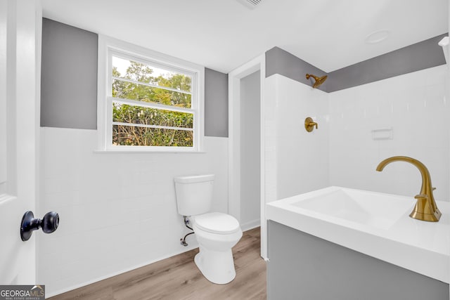 bathroom with tile walls, vanity, a tile shower, toilet, and hardwood / wood-style floors