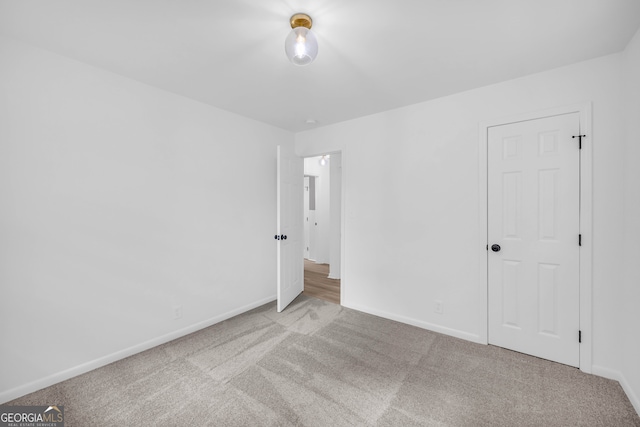 unfurnished bedroom featuring light colored carpet and a closet