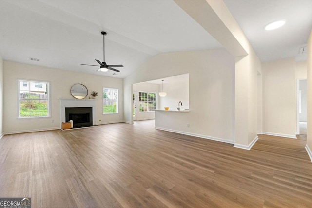 unfurnished living room with ceiling fan, hardwood / wood-style floors, and vaulted ceiling