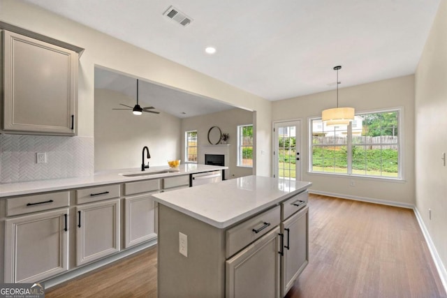 kitchen with ceiling fan, dishwasher, sink, a center island, and backsplash