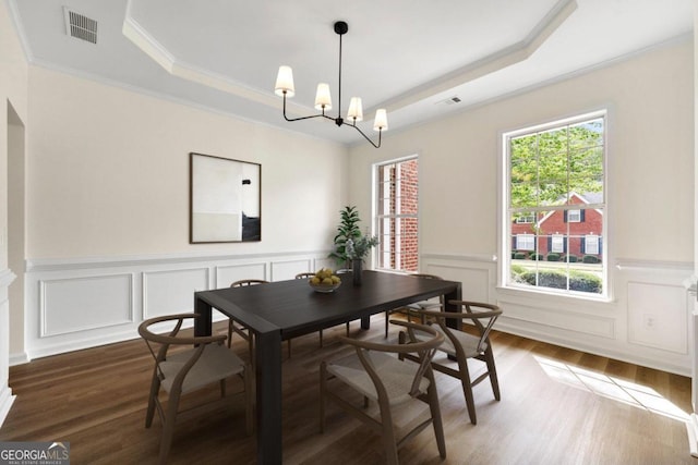 dining space featuring a raised ceiling, dark hardwood / wood-style flooring, crown molding, and a chandelier