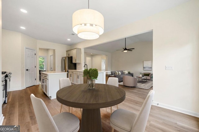 dining area featuring ceiling fan, light hardwood / wood-style floors, lofted ceiling, and sink