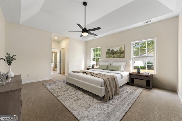 carpeted bedroom featuring connected bathroom, a raised ceiling, and ceiling fan