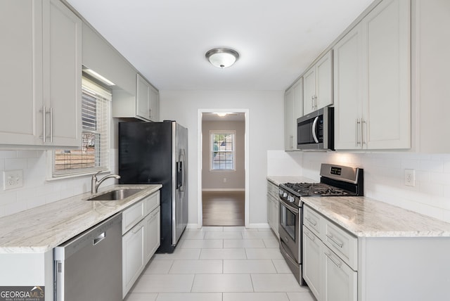 kitchen featuring white cabinetry, sink, light stone countertops, and appliances with stainless steel finishes