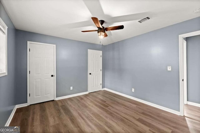 unfurnished bedroom with ceiling fan and dark hardwood / wood-style flooring