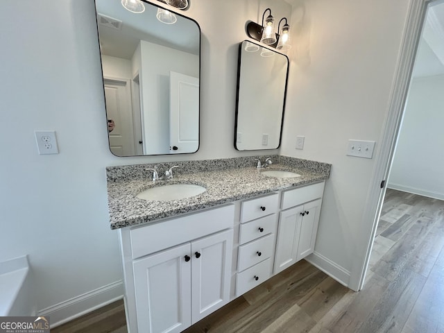 bathroom with double vanity, visible vents, a sink, and wood finished floors