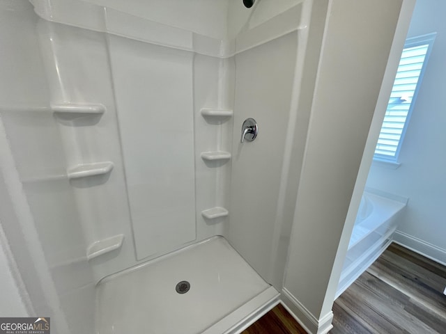 bathroom with baseboards, wood finished floors, and a shower stall