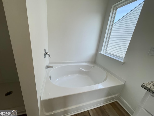 bathroom featuring plenty of natural light, a bath, and wood finished floors