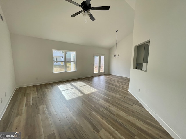 unfurnished living room with french doors, dark wood-type flooring, high vaulted ceiling, baseboards, and ceiling fan with notable chandelier