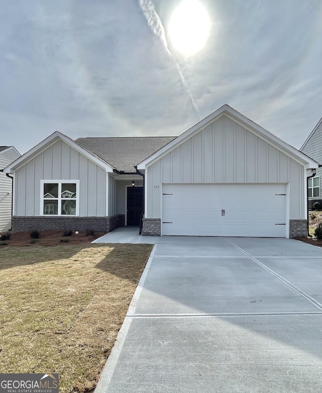 view of front of home featuring driveway, a garage, a front yard, board and batten siding, and brick siding