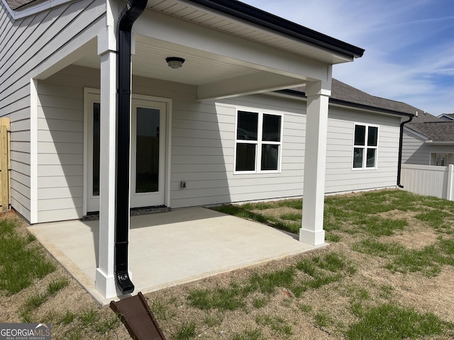 exterior space with roof with shingles, fence, and a patio