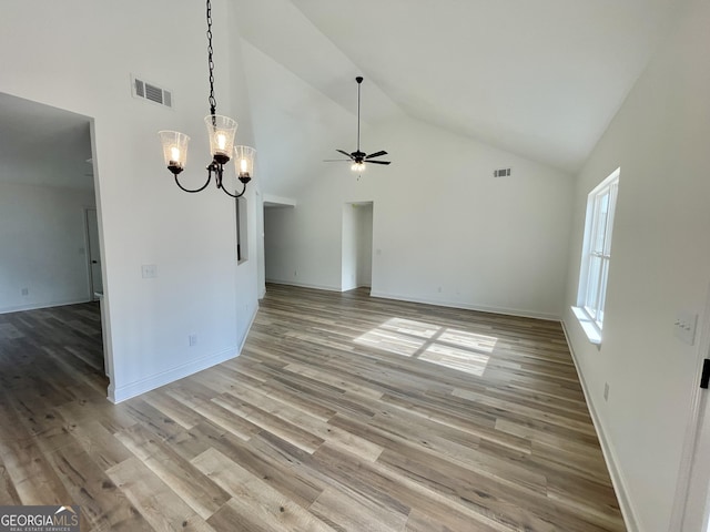 empty room with high vaulted ceiling, light wood-style flooring, and visible vents