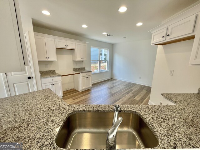 kitchen with light wood-type flooring, white cabinets, recessed lighting, and light stone countertops