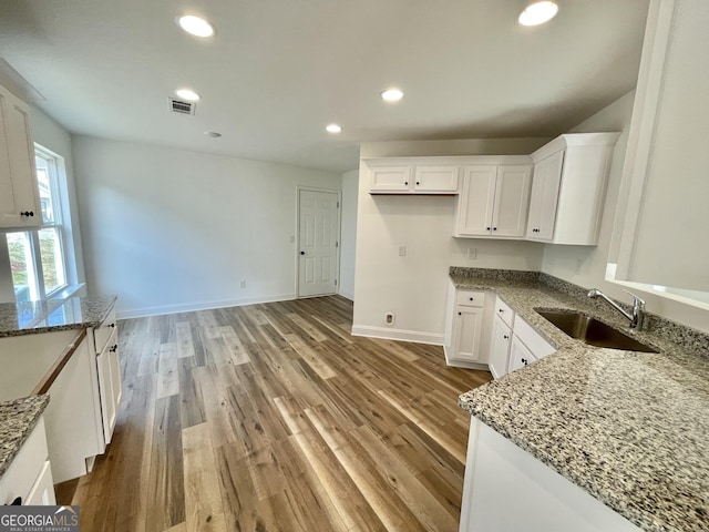 kitchen with visible vents, a sink, white cabinetry, and light stone countertops