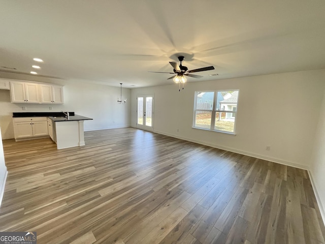 unfurnished living room featuring light wood finished floors, ceiling fan, baseboards, and french doors