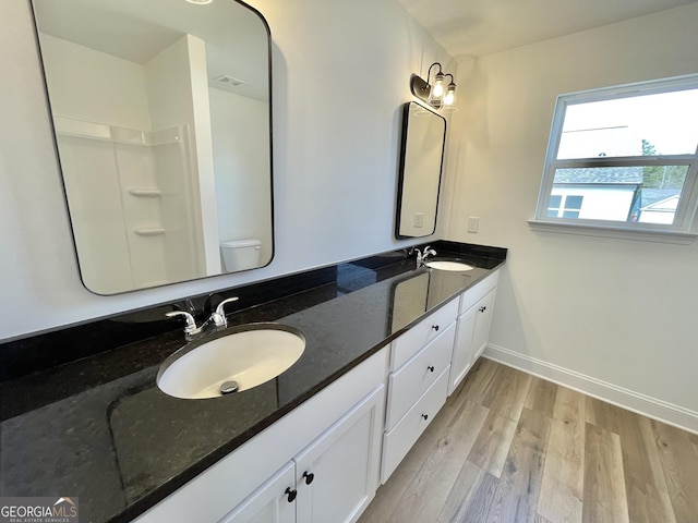 bathroom with double vanity, toilet, a sink, and wood finished floors