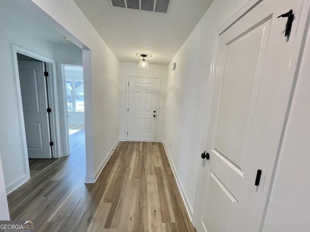 hall with visible vents, baseboards, and wood finished floors