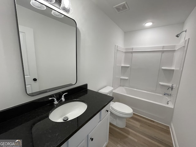 bathroom with visible vents, shower / bathing tub combination, toilet, vanity, and wood finished floors