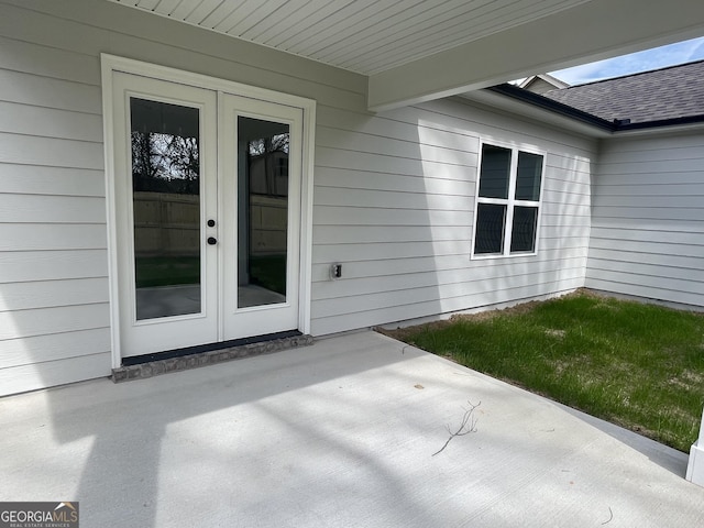 property entrance with a patio, french doors, and a shingled roof