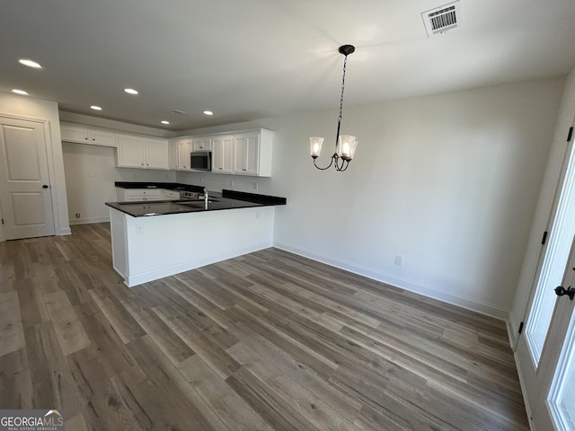 119 Savannah Way Unit C10, Milner, GA 30257 - kitchen featuring stainless steel microwave, dark countertops, a peninsula, dark wood-style flooring, and recessed lighting