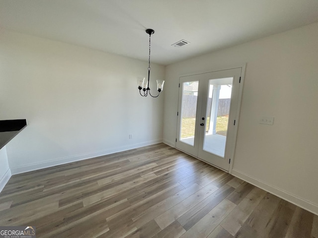 unfurnished dining area with light wood-style flooring, visible vents, a chandelier, and baseboards